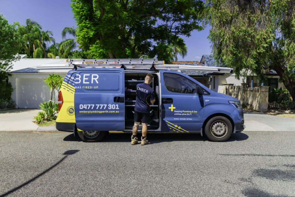 Ember Plumbing Perth tradie accessing tools from a branded service van parked outside a suburban home in Perth