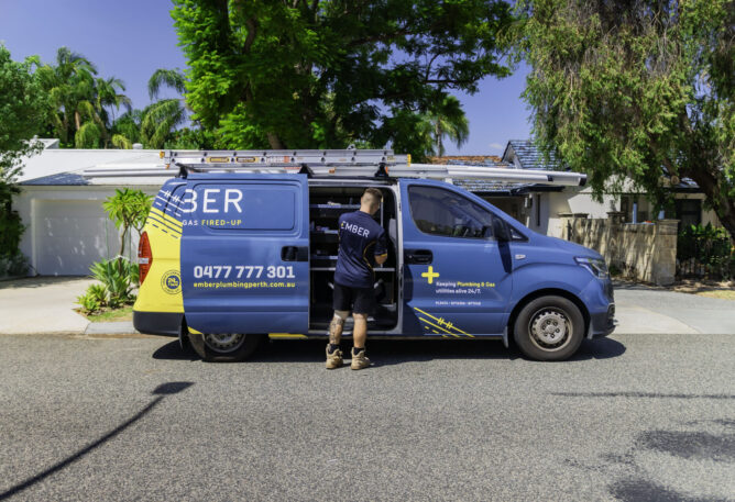 Ember Plumbing Perth tradie accessing tools from a branded service van parked outside a suburban home in Perth
